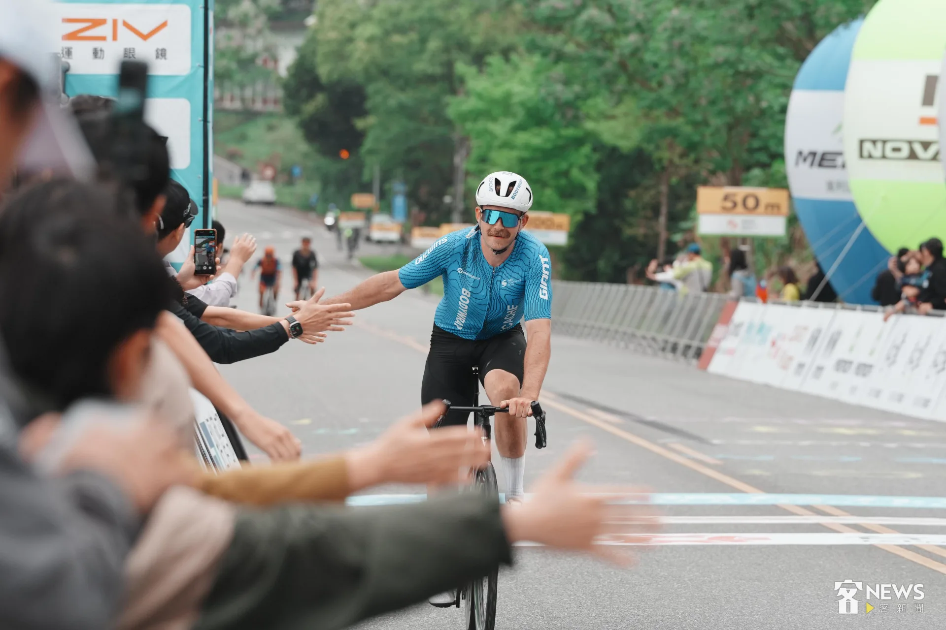 落後的選手展現運動家風度，落後仍騎完成全程，並與場邊加油群眾擊掌。李台源攝