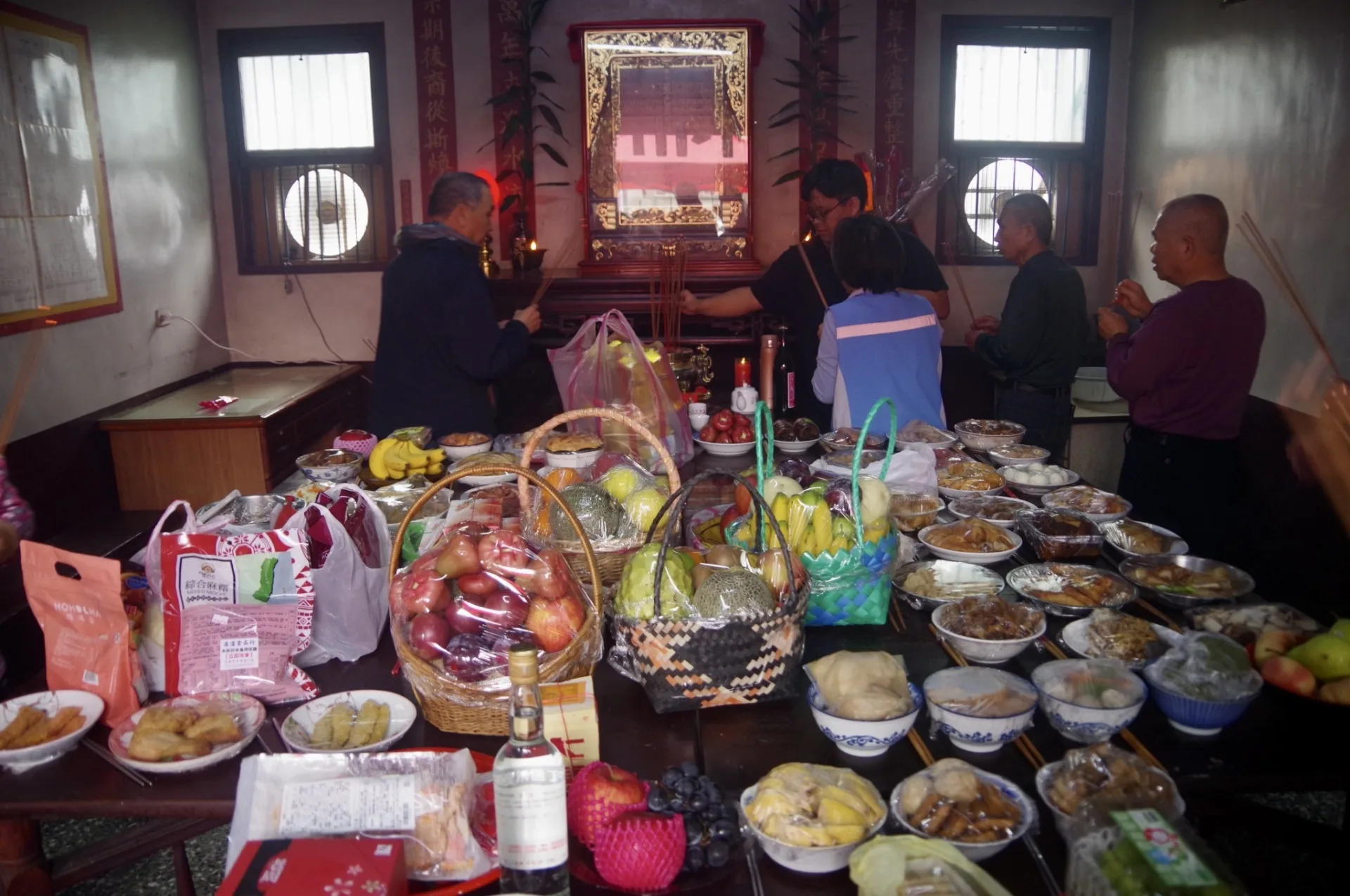 黎屋宗親們齊聚公廳，在煙霧繚繞中虔誠祭拜，碗盤內盡是美味佳餚。徐彩雲攝