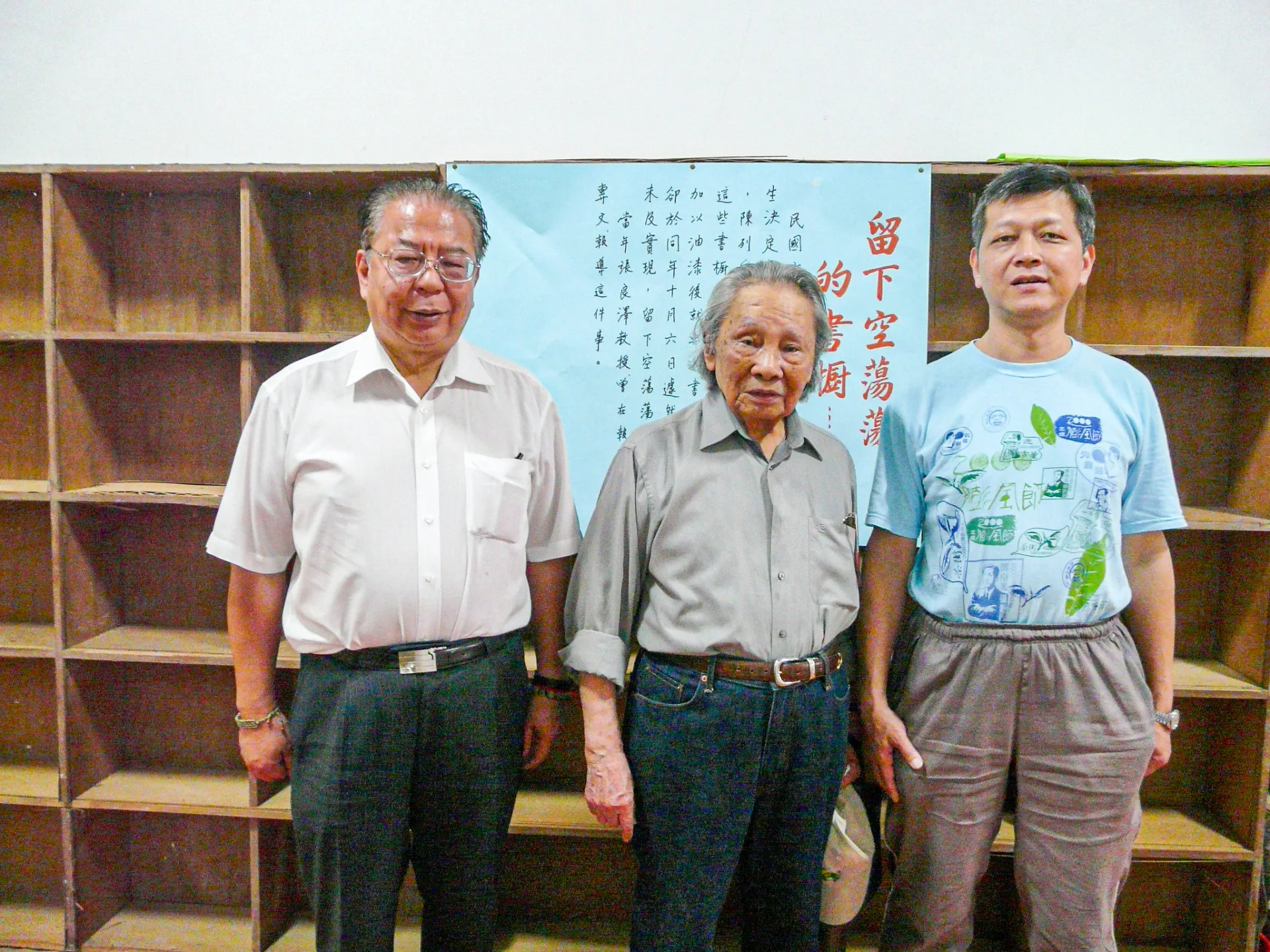 當初吳濁流在世時，想把新埔故居至德堂改成台灣文藝資料館，且訂製好新的書櫃，用來陳列台灣作家們的作品。天不從人願，上漆後準備將書運進來，吳濁流驟然長逝，願望來不及完成，留下空蕩蕩的書櫃。鍾老每一次來都會在這裡逗留許久。鍾老（中）、盧孝治（左）與我（右）。2011，新埔，楊國鑫提供
