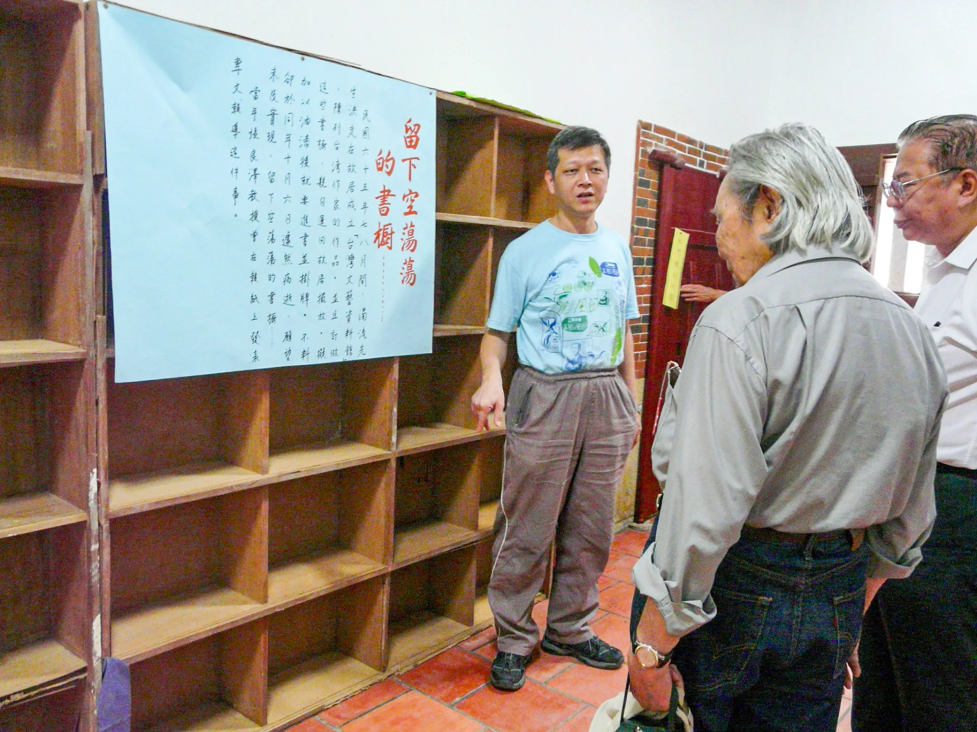 當初吳濁流在世時，想把新埔故居至德堂改成台灣文藝資料館，且訂製好新的書櫃，用來陳列台灣作家們的作品。天不從人願，上漆後準備將書運進來，吳濁流驟然長逝，願望來不及完成，留下空蕩蕩的書櫃。鍾老每一次來都會在這裡逗留許久。鍾老（中）、盧孝治（右）與我（左）。2011，新埔，楊國鑫提供