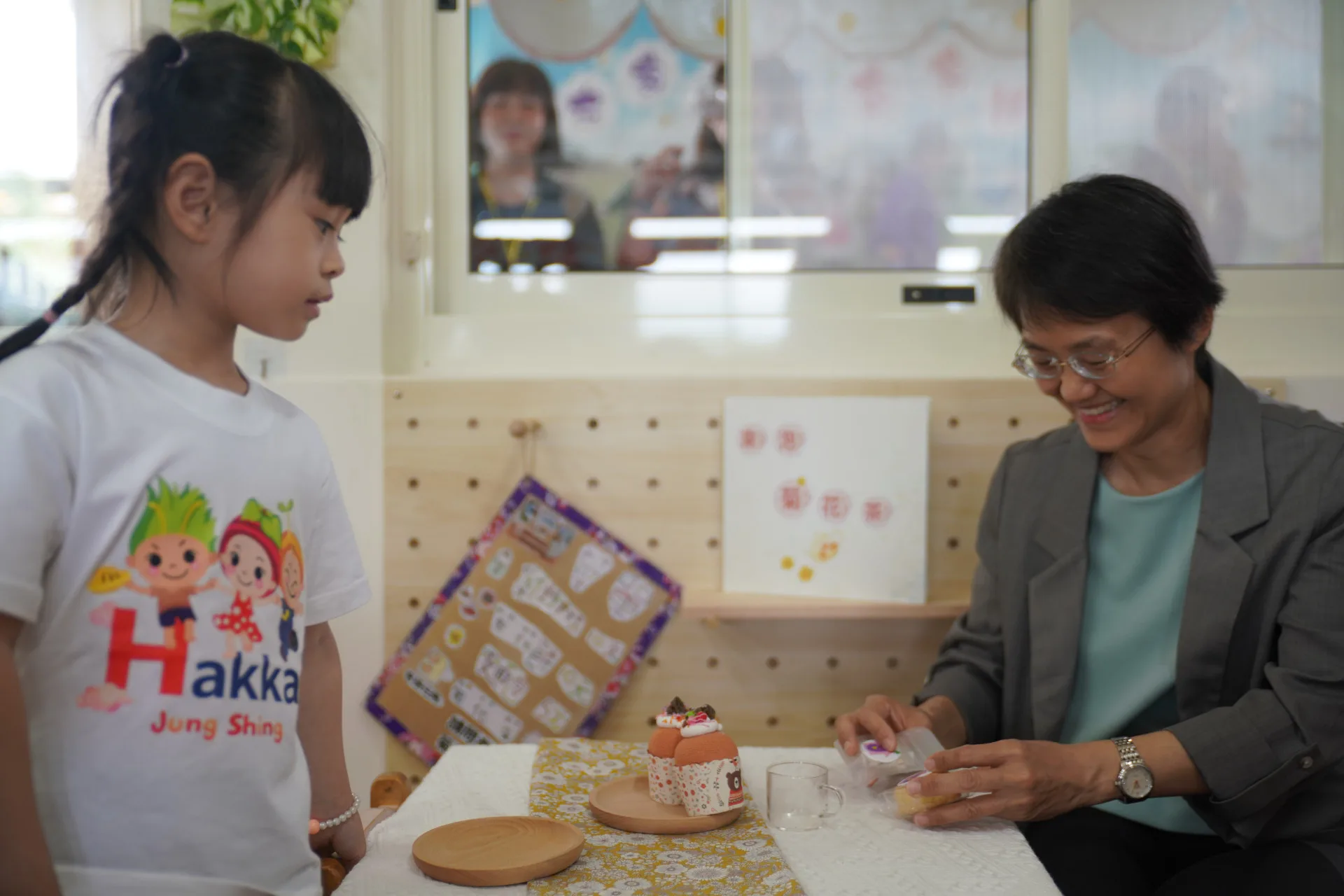 苗栗縣銅鑼鄉中興國小幼兒園孩童扮演小老闆,認真說客語推廣菊花茶點。廖文琪攝