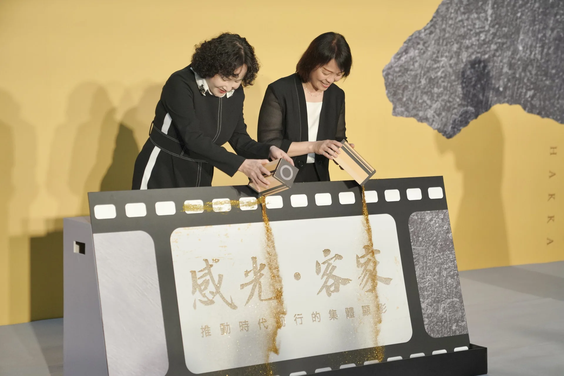 中央社社長胡婉玲與客委會副主委廖育珮用金砂替「感光・客家」進行「顯影」啟動儀式。莊勝鴻攝