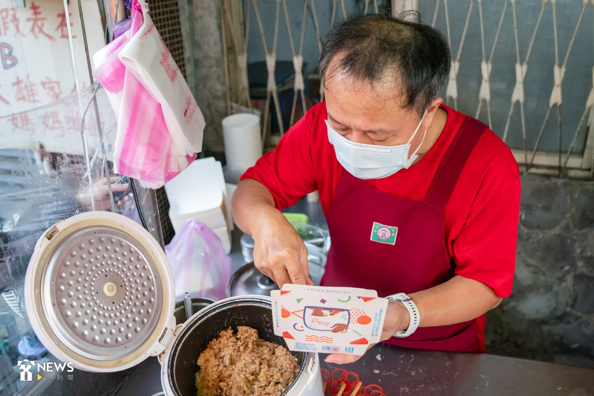 老闆「葉大雄」帶著口罩、掛起圍裙,將電鍋中的金黃油飯裝入盒中。洪藝晅攝