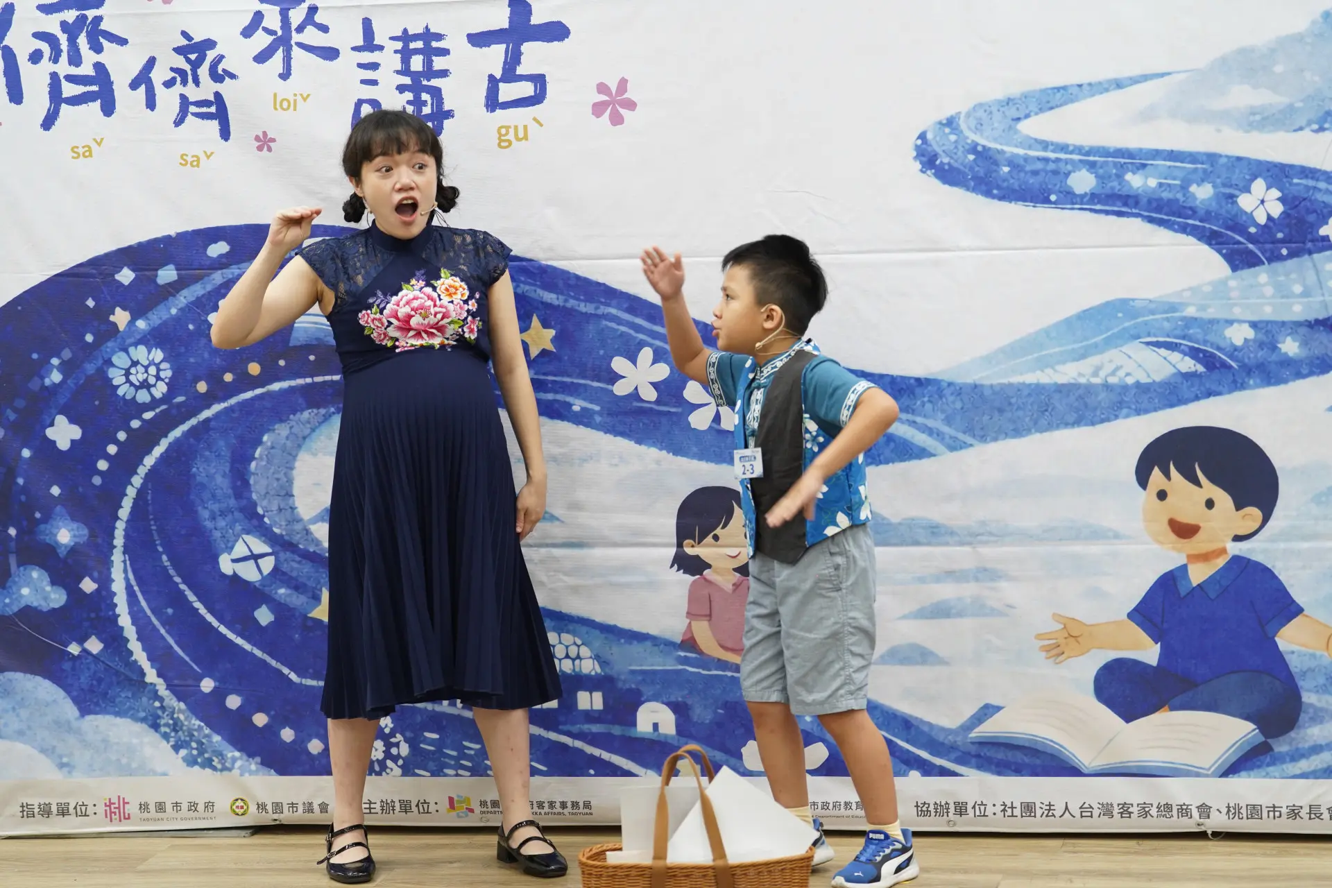 幼兒親子組鄒程安小朋友(右)及媽媽李韻慈(左)自創故事〈伯公轉屋〉,以精采客語口說及豐富肢體表現拿下冠軍。桃園市客家局提供