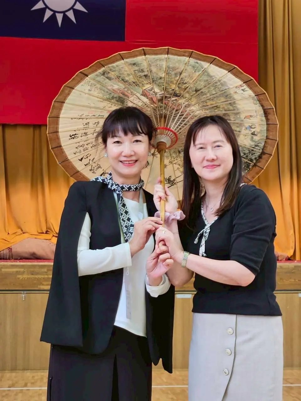 楊瑞霞致贈美濃紙傘給校長吳育珊。高市客委會提供