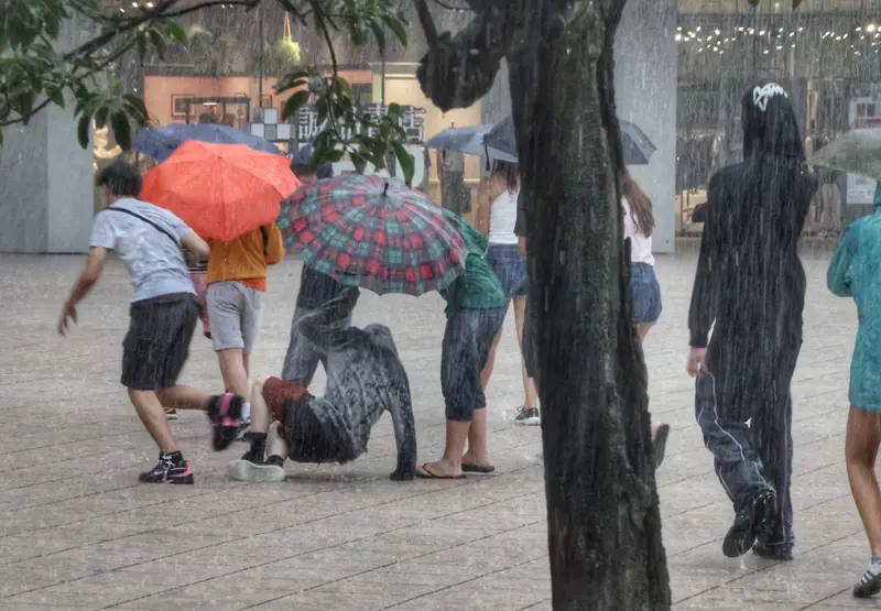 中央氣象署發布豪雨特報，午後對流雲系發展旺盛，易有短延時強降雨，圖為18日下午台北下起大雨，民眾在松山文創園區不慎跌倒。中央社