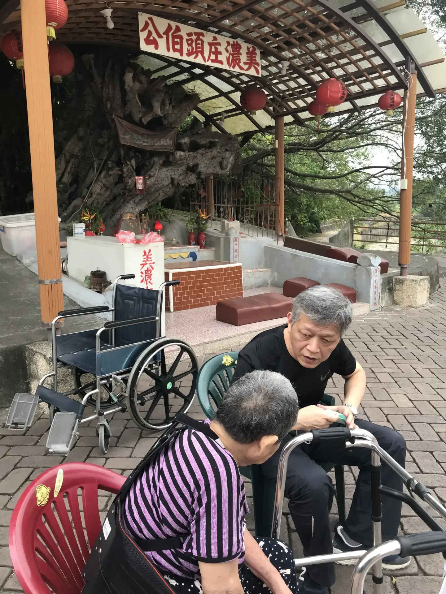 我到高雄美濃參訪,巧遇小時候隨父母親從新竹新埔南下高雄旗山耕田的阿婆,現在跟女兒住在美濃,我們在美濃庄頭伯公前聊了起來。2021,高雄美濃。楊國鑫提供