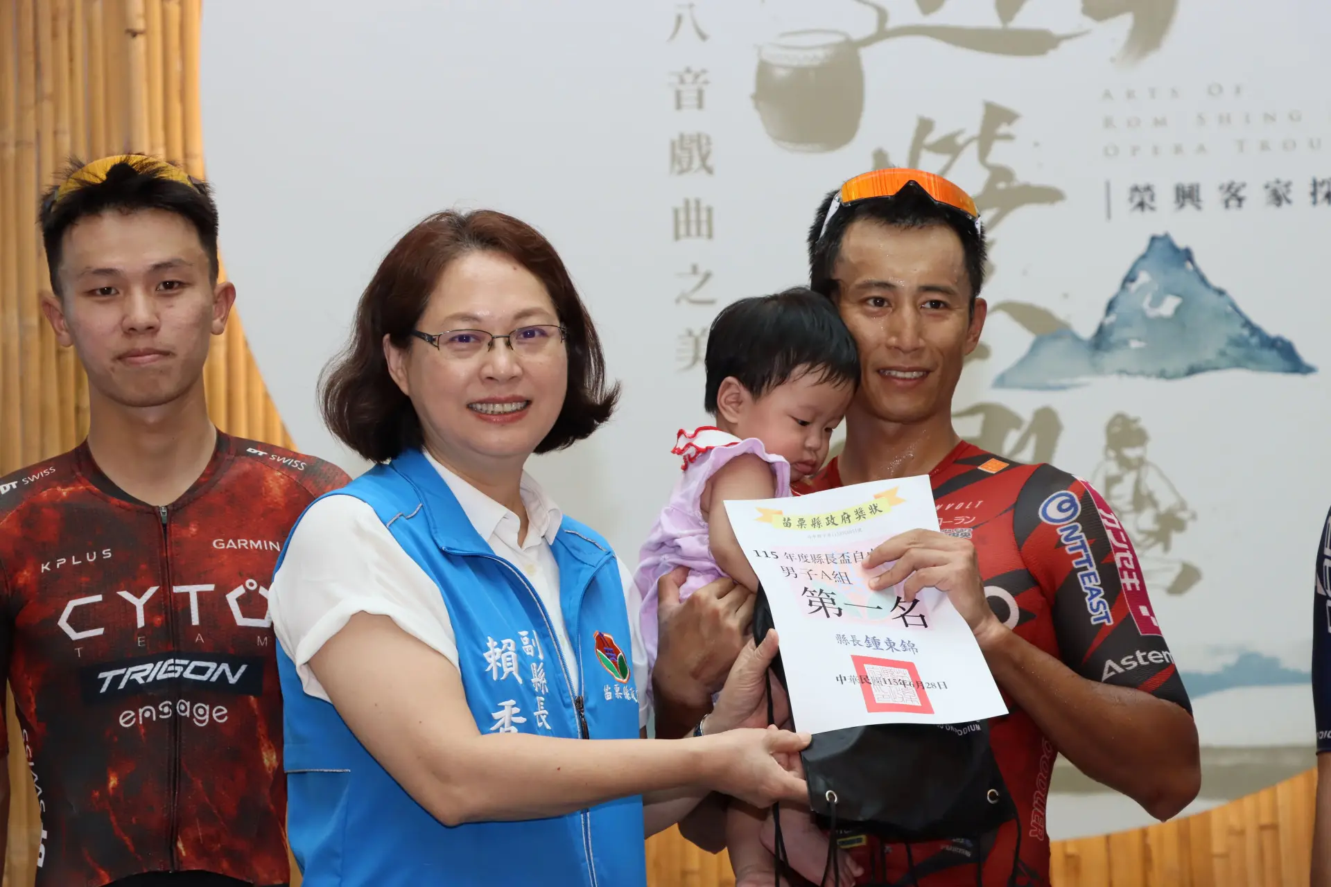 男子A組冠軍國手馮俊凱抱著愛女,從苗栗縣副縣長賴香伶手中接下冠軍獎狀。苗栗縣政府提供