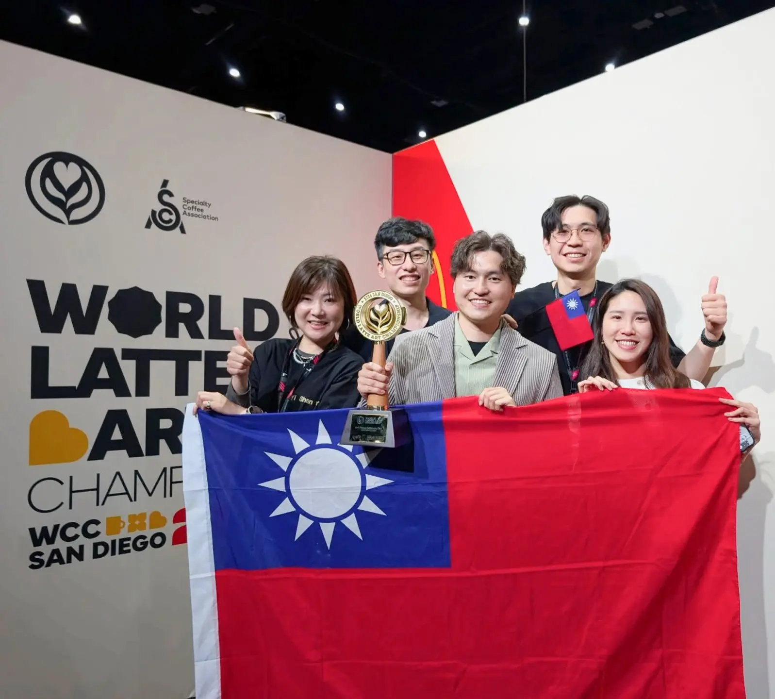 「2026 WCC 世界拉花大賽」台灣代表冠軍得主林紹興奪冠後開心拿著國旗與團隊合影。翻攝林紹興IG(bala_1217)