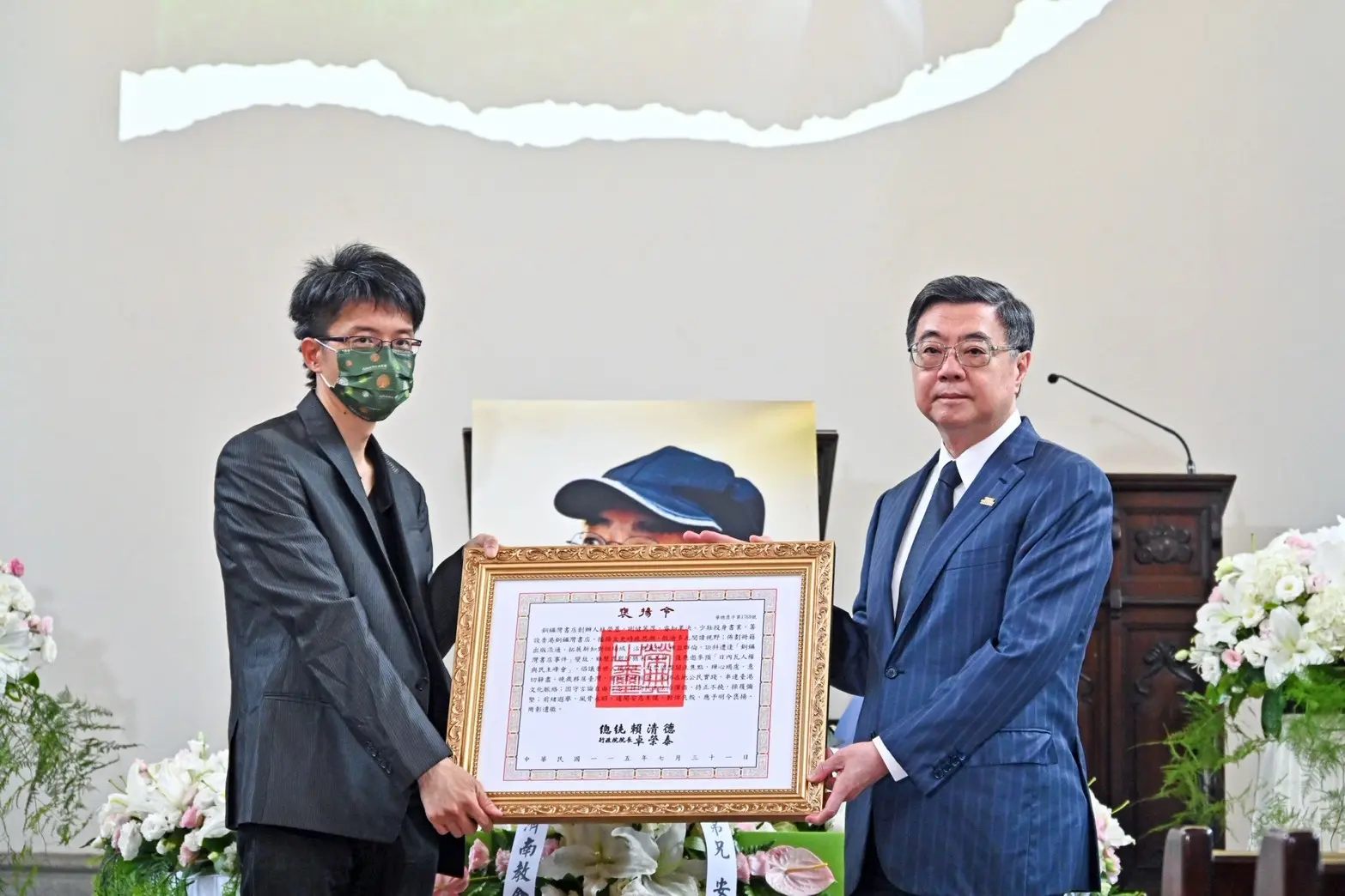 行政院長卓榮泰（右）31日出席銅鑼灣書店店長林榮基的告別禮拜，並代表總統賴清德頒贈褒揚令，由林榮基長子林靈均（左）代表受贈。行政院提供