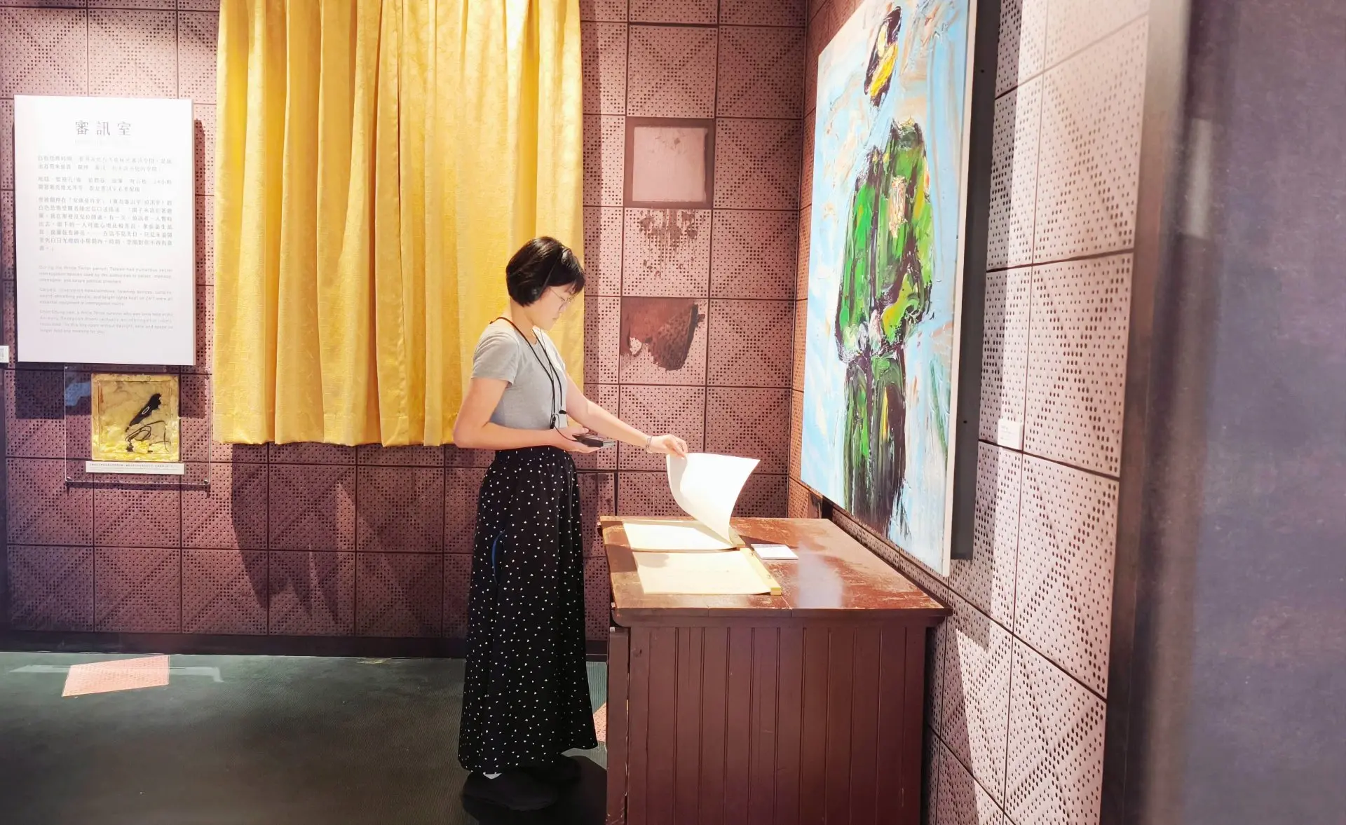 觀眾在「自由花蕊」展場內邊聽語音導覽、邊翻閱現場展示的黃信介自白書。國立中正紀念堂管理處提供