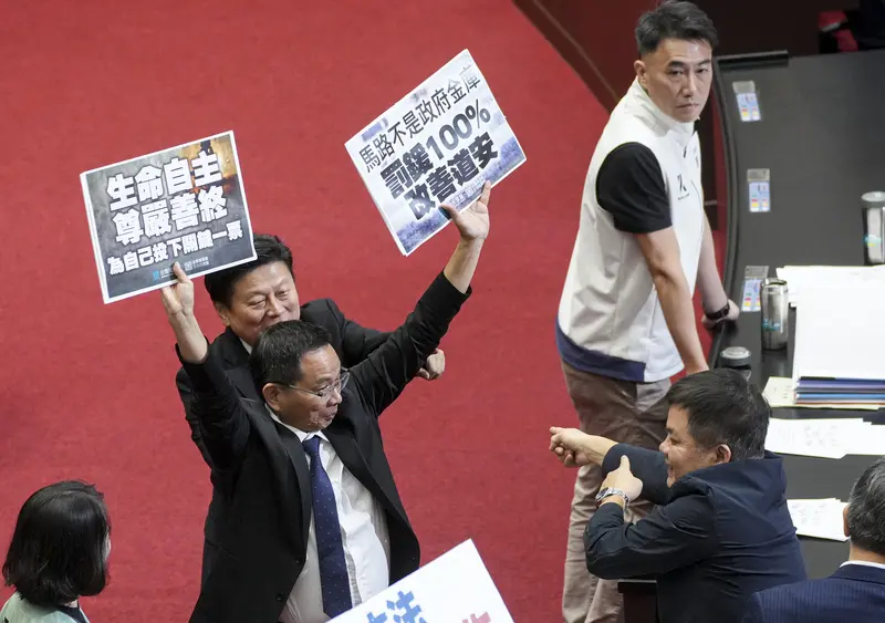 民眾黨團總召陳清龍（前左）舉起寫有「馬路不是政府金庫」、「生命自主尊嚴善終」等標語手板支持公投，安樂死提案未通過。中央社