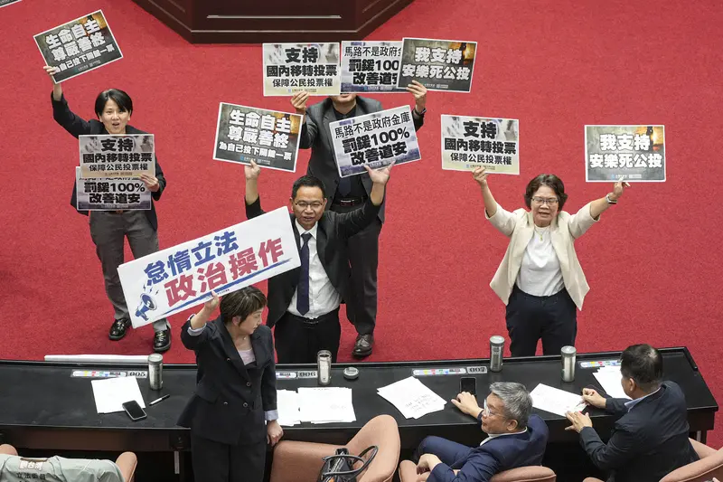 立法院會14日處理公投提案，民眾黨團總召陳清龍（站者中）率黨團立委舉牌表達支持安樂死法制化、交通違規罰鍰專款專用及國內移轉投票等公投訴求，民進黨團書記長范雲（前左）則舉起「怠惰立法、政治操作」手板表達反對。中央社