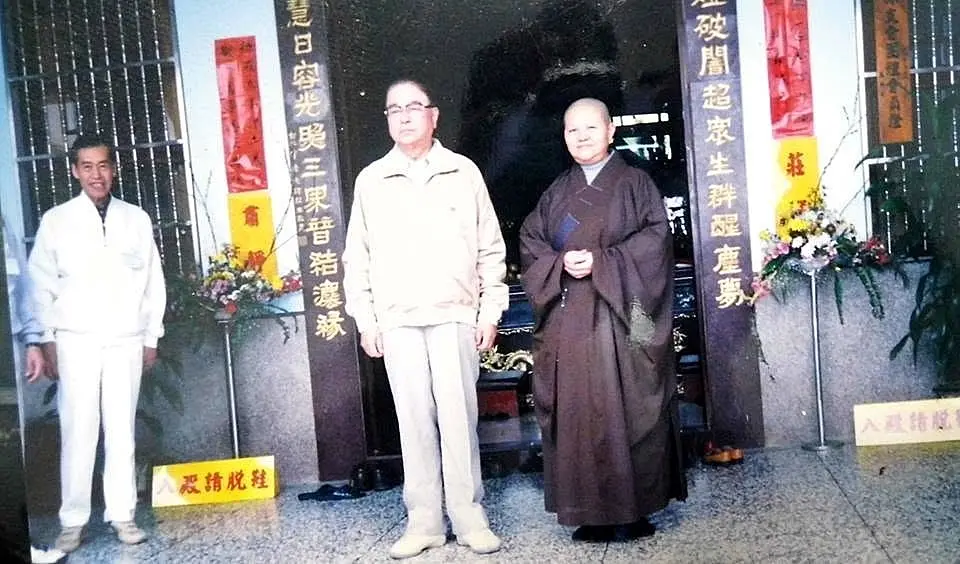 替林洋港在獅頭山水濂洞前,與主持合拍張照片。陳權欣攝