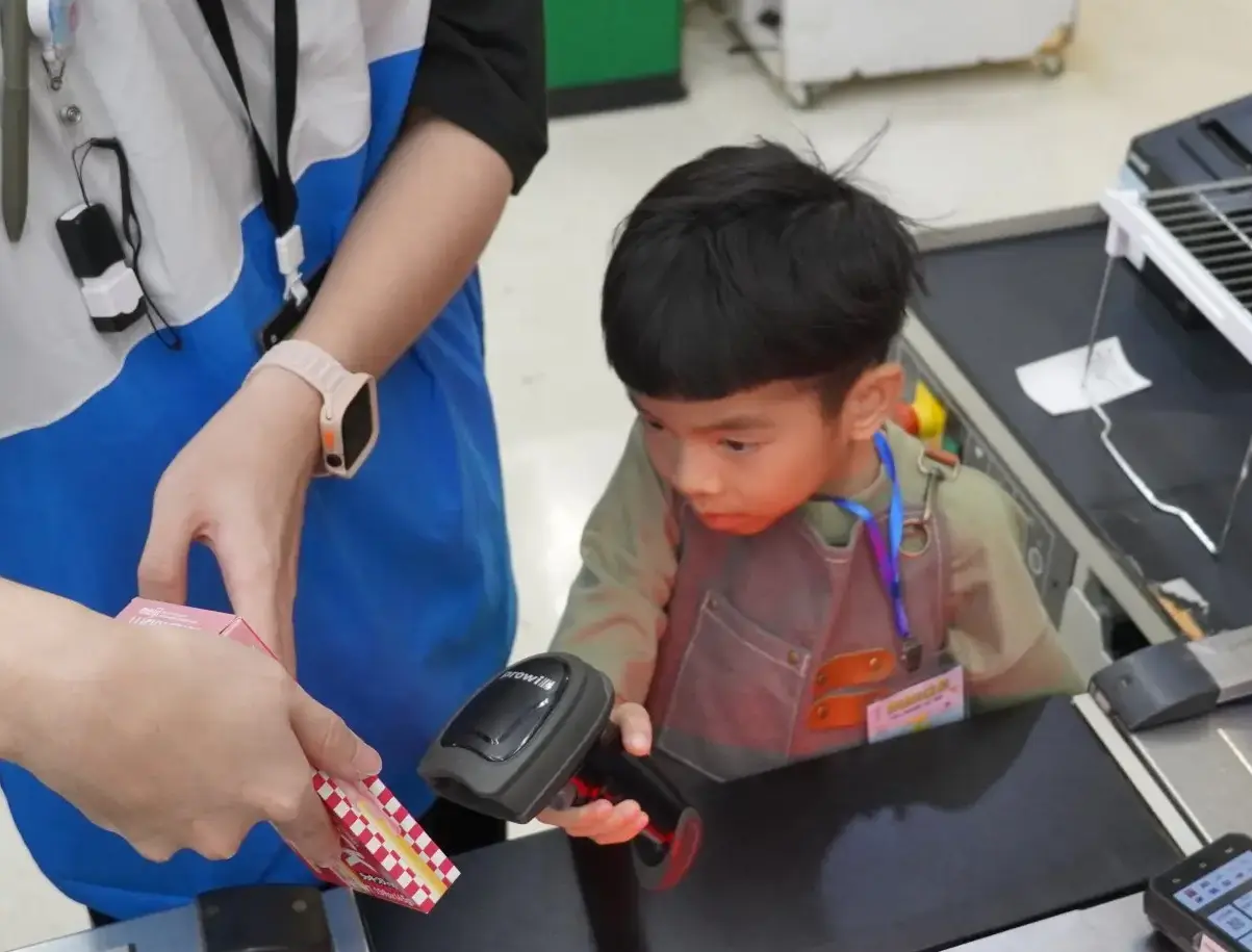 孩子穿上圍裙、掛起名牌,化身「細細店長」,在賣場中體驗客語學習。林鴻文攝