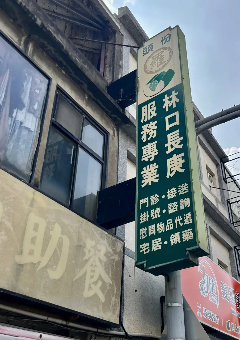 醒目的綠底白字老招牌，標示著「林口長庚服務專業」，提供門診、接送、掛號與代遞等在地生活服務。攝於2026年。徐彩雲攝
