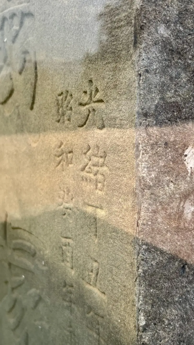 隔著玻璃罩，仍可辨認義塚石碑上的「光緒」刻字。徐彩雲攝