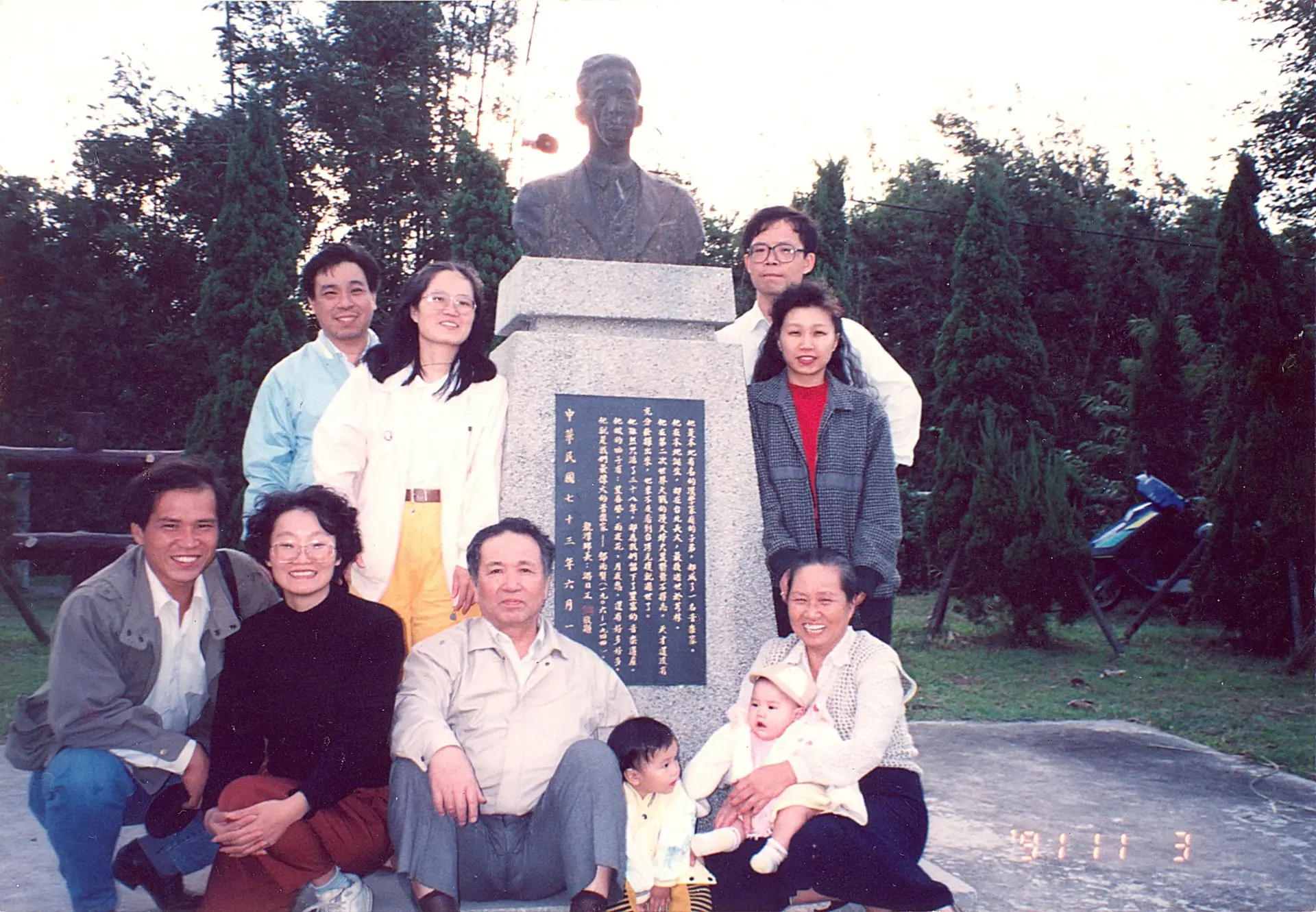 芎林國中的校歌是鄧仁輔(前排左三)老師作曲，這照片是鄧仁輔帶著全家到龍潭，於父親鄧雨賢紀念銅像前合影。本照片典藏者：鄧泰超/發佈於「開放博物館」官網。