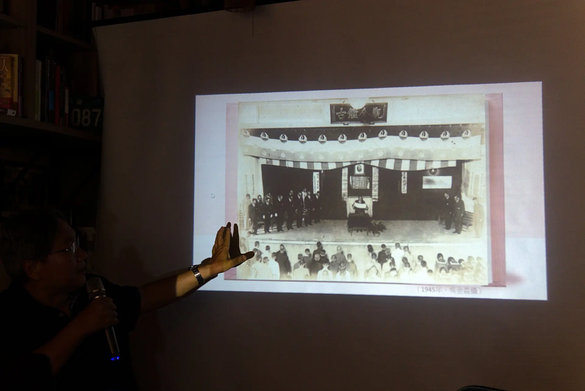 作者解析〈光復節大會〉中的「觀今鑑古」匾額、舞台裝飾、台下學生們等背後令人玩味的意涵。廖文琪攝