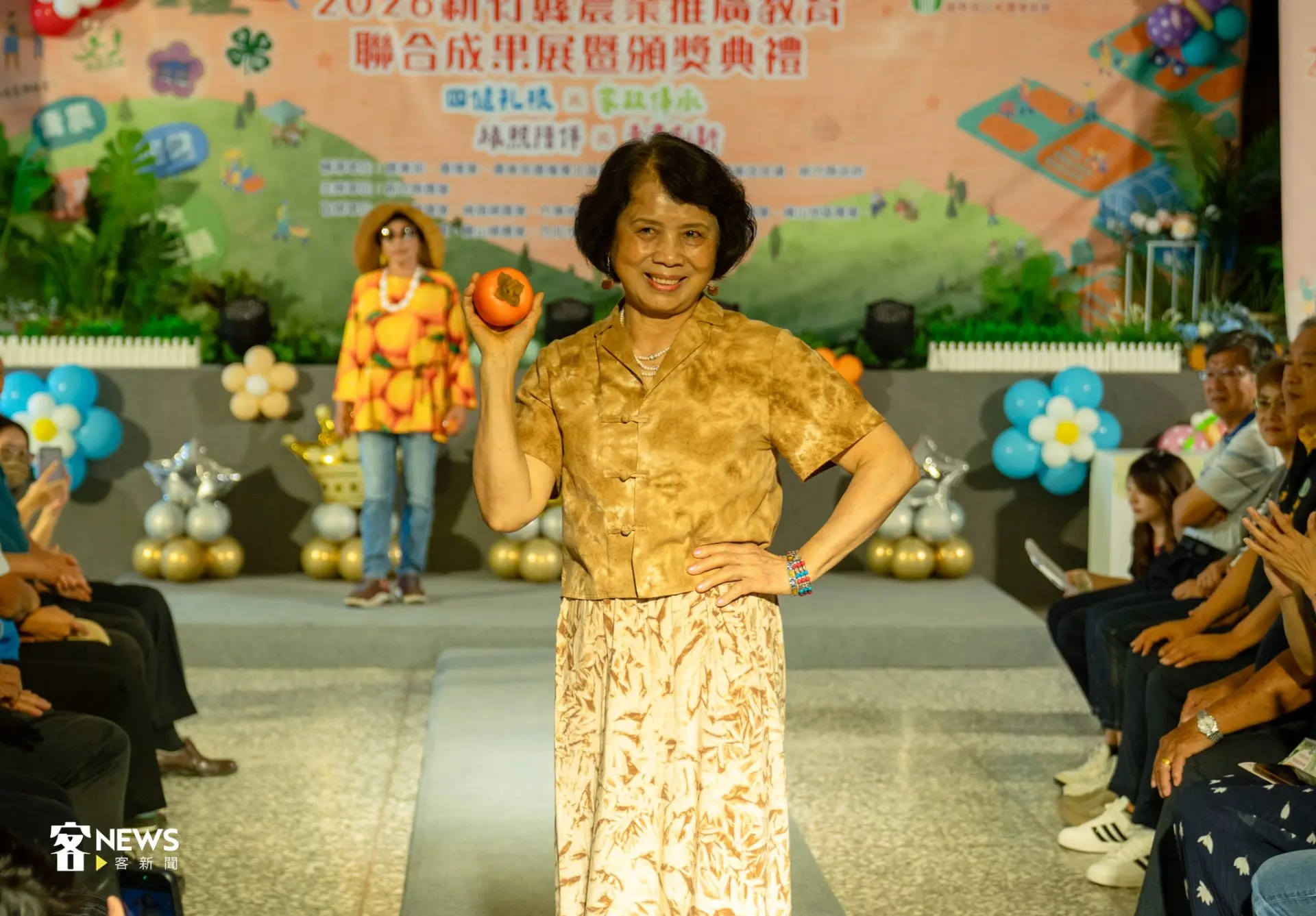 新埔鎮農會家政班成員手拿柿子，將柿染穿上身。李宥妍攝