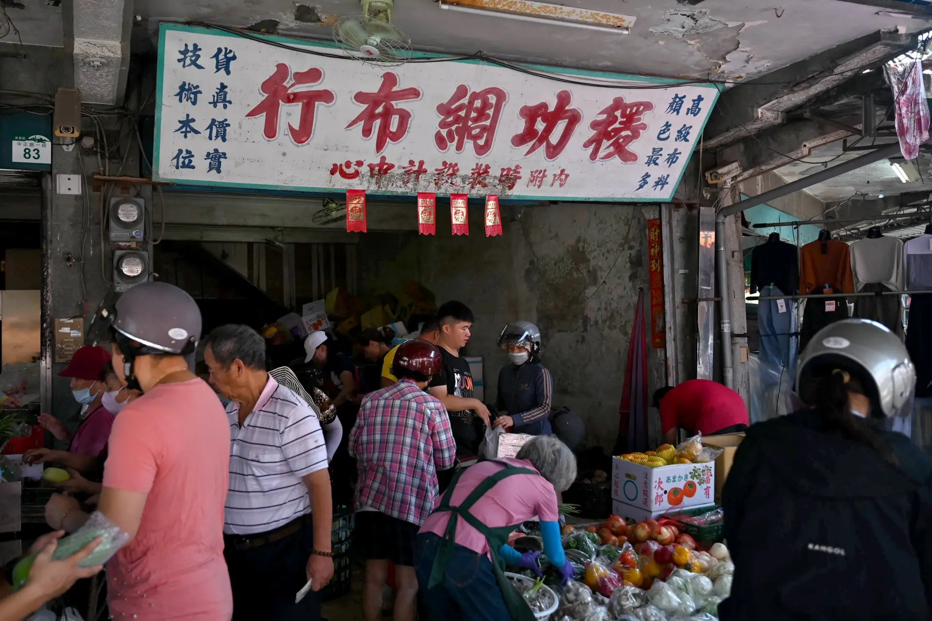 熱鬧的菜攤上方，仍掛著「稷功綢布行」的老招牌。Haka小姐攝
